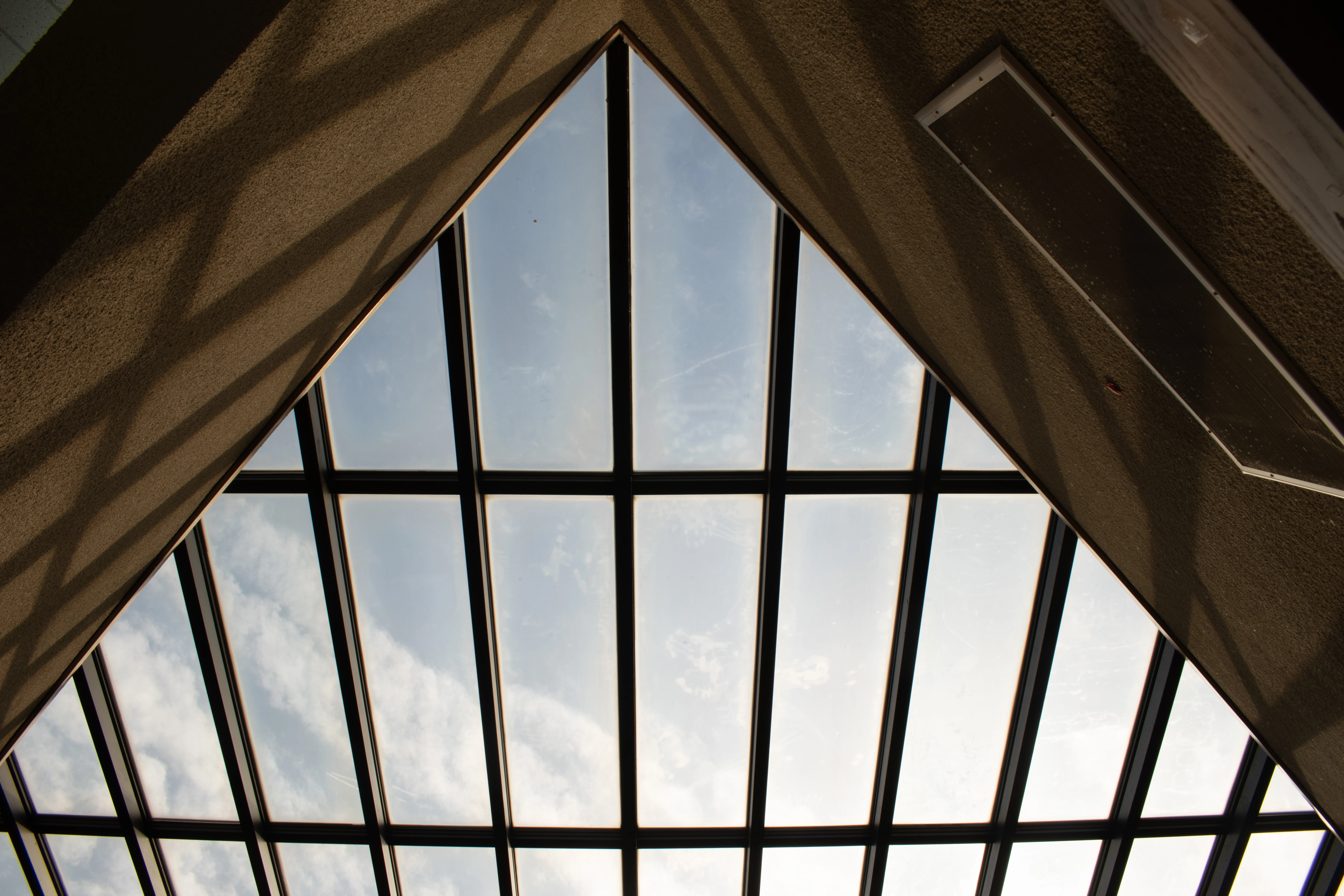 A Polaroid of a vaulted window with many panes and clear blue sky