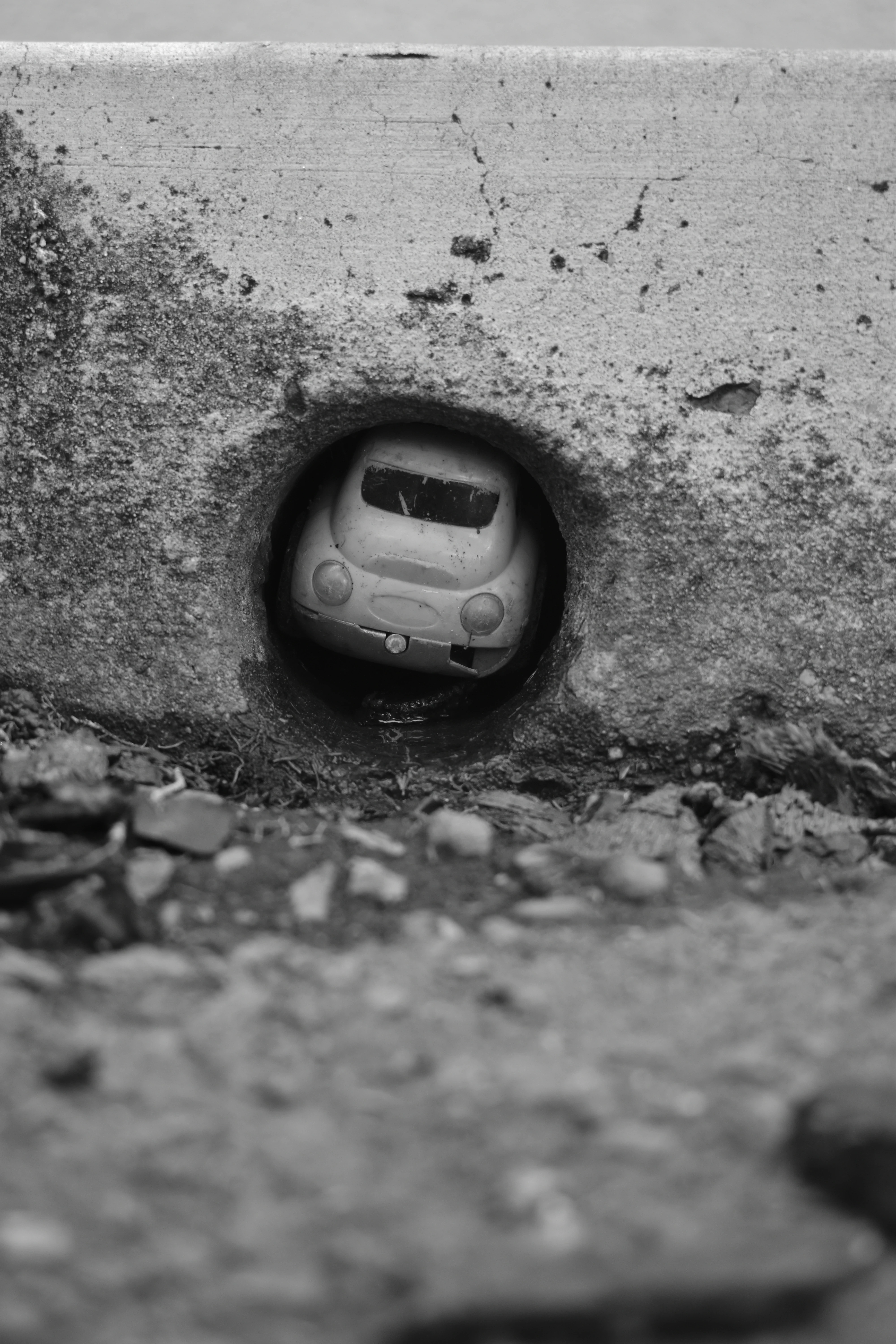 A Polaroid of a childs toy car stuck in a drain hole