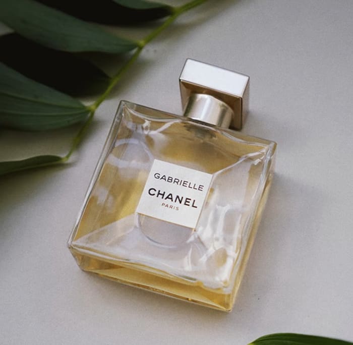 Gabrielle Essence Eau De Parfum bottle surrounded by leaves