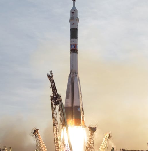 A rocket launching, clouds of smoke billowing from the launch pad